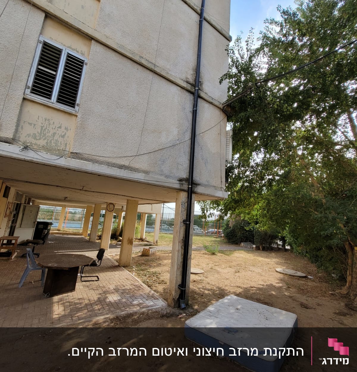 מזרן ישן מונח על הקרקע ליד בניין